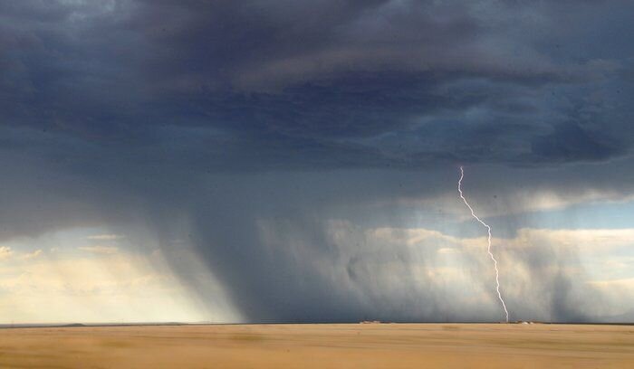 A picture of a bolt of lightning striking a plain during a storm.