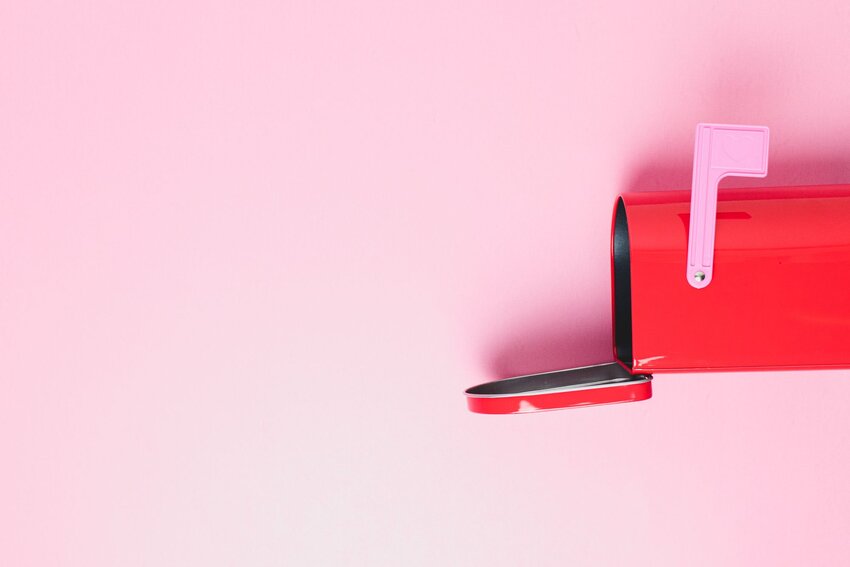 An image of an open red mailbox against a pink background.